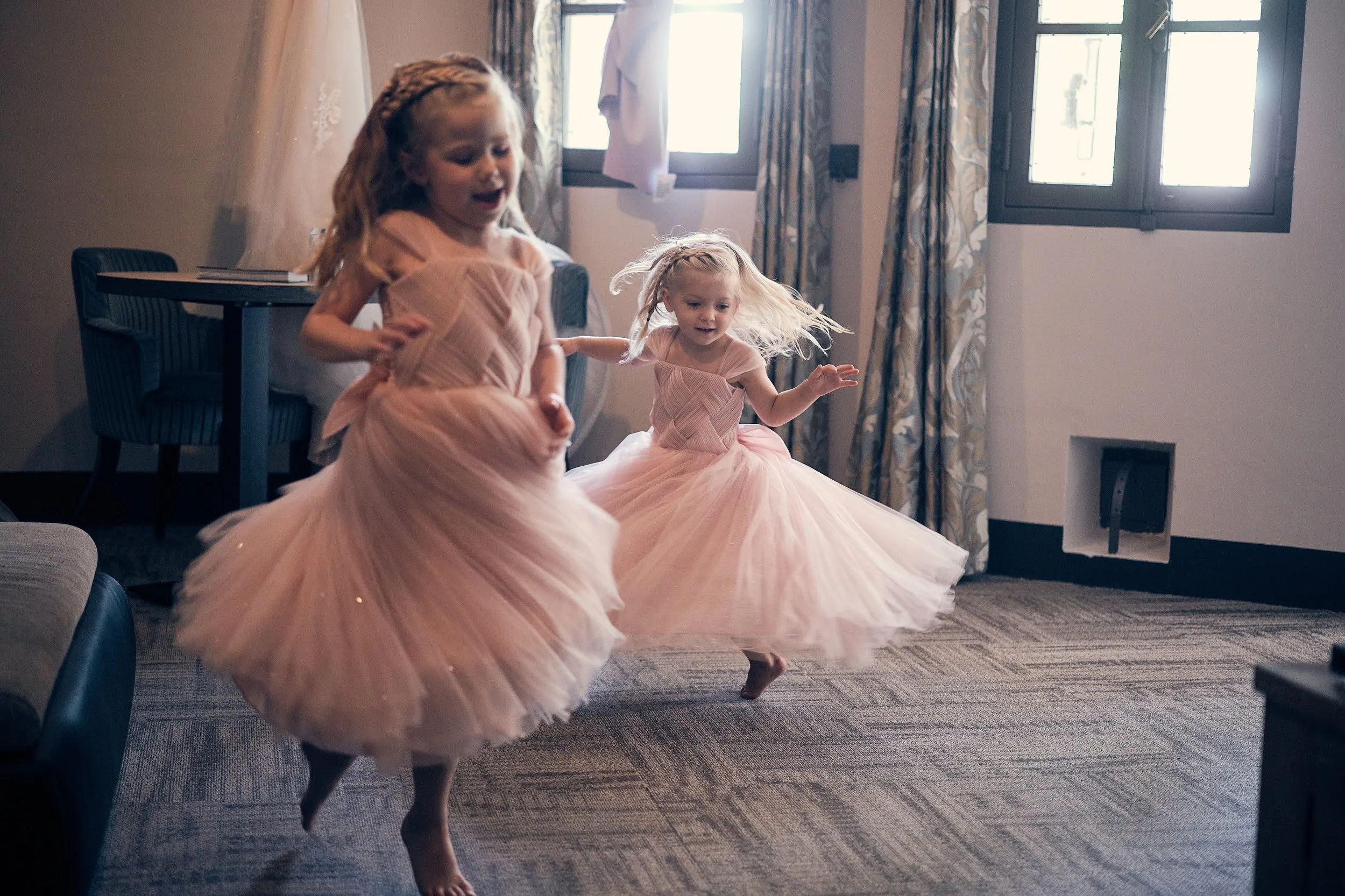 Twee bruidsmeisjes dansen uitgelaten in roze tule jurken in de bruidssuite op Fort Beemster