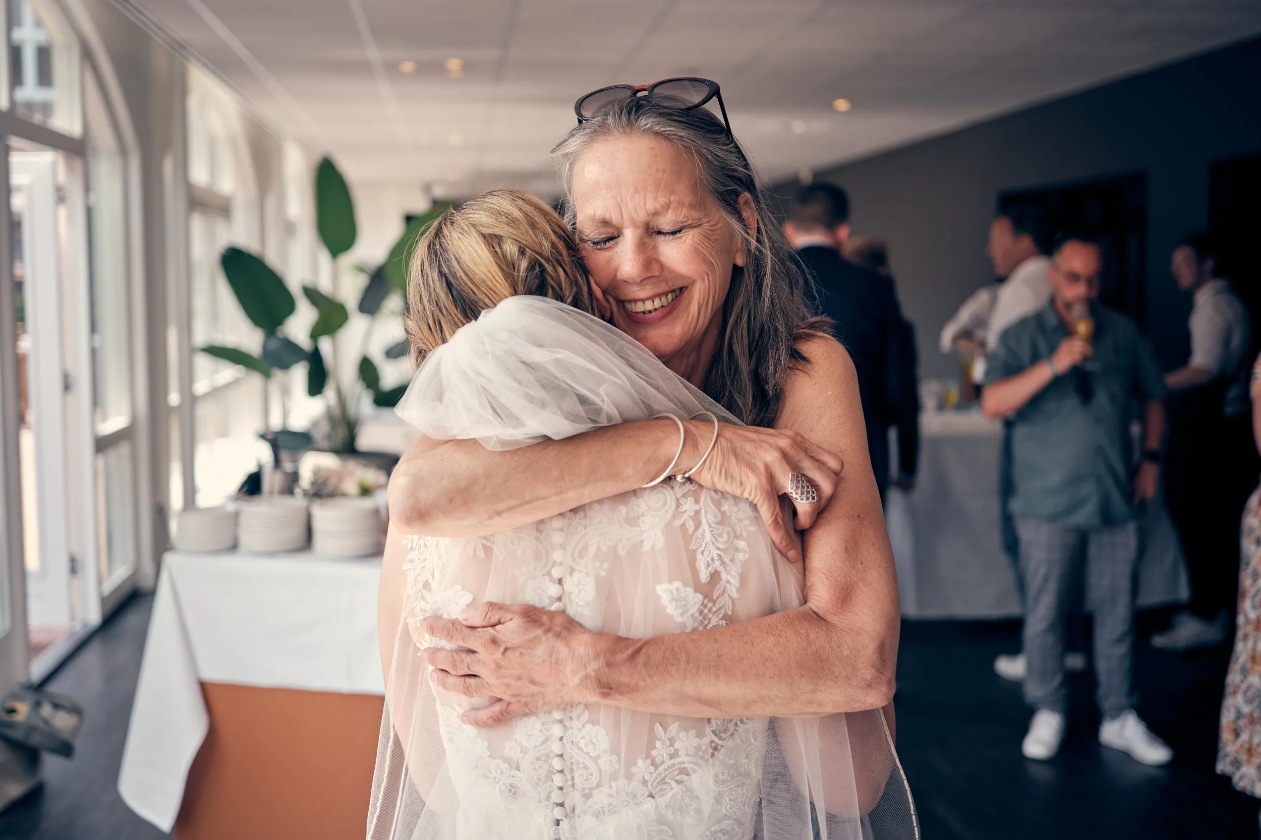 Moeder van de bruid omhelst haar dochter in trouwjurk met emotie en blijdschap op het feest