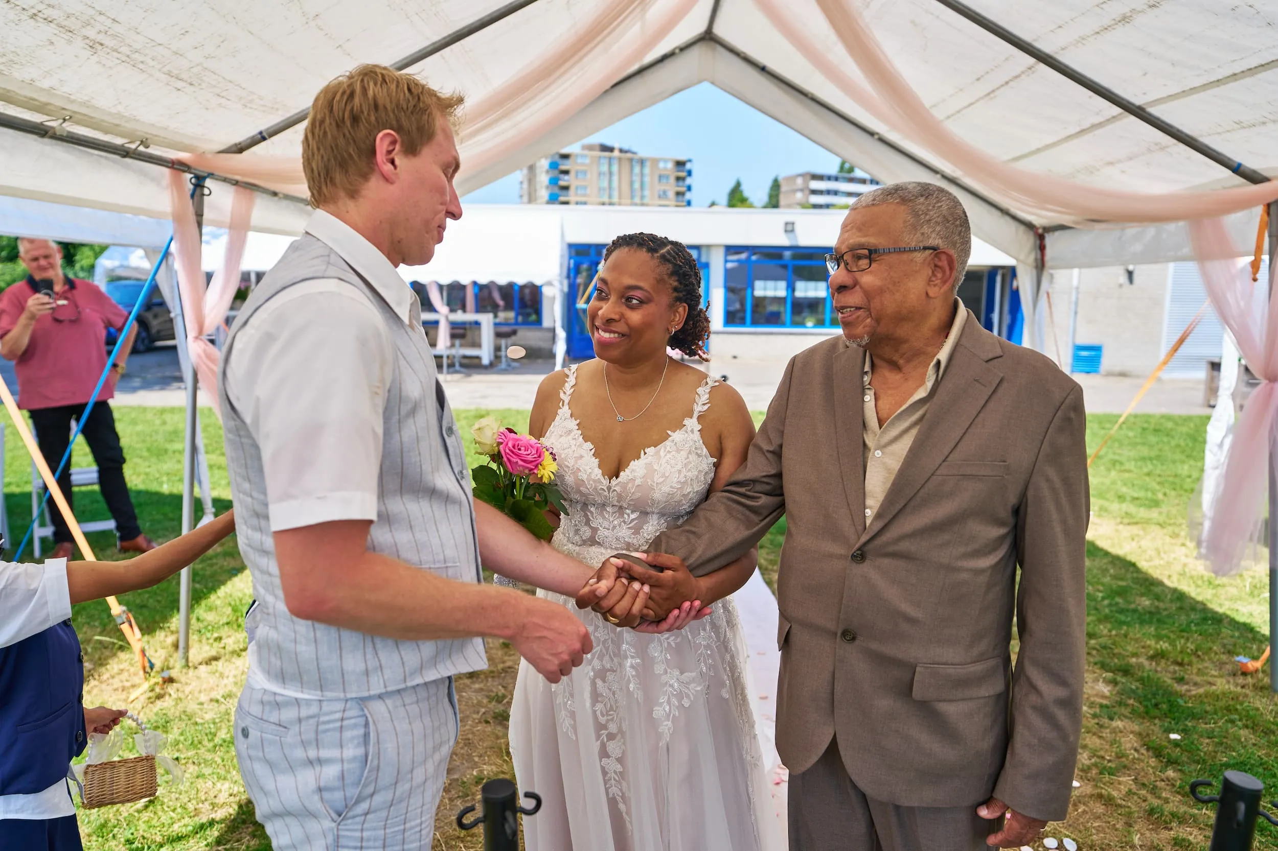 Bruidspaar begroet vader onder decoratieve tent op bruiloft in Zoetermeer, emotioneel moment — Trouwshoot Stefan Segers