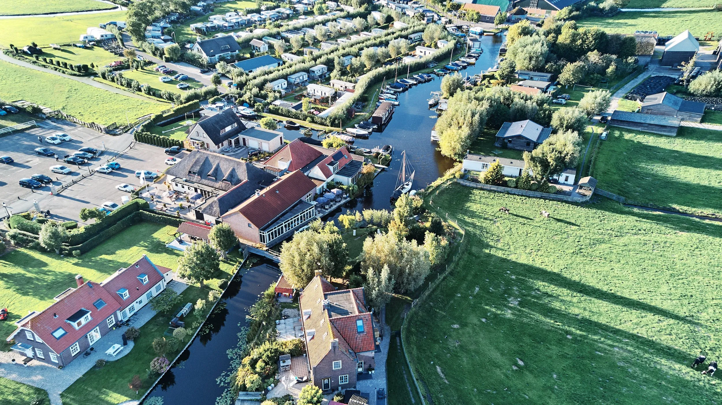 Luchtfoto van bruidspaar Patrick en Lyn bij Meerhoeve in Oud Ade, met pittoresk Nederlands landschap en kanalen