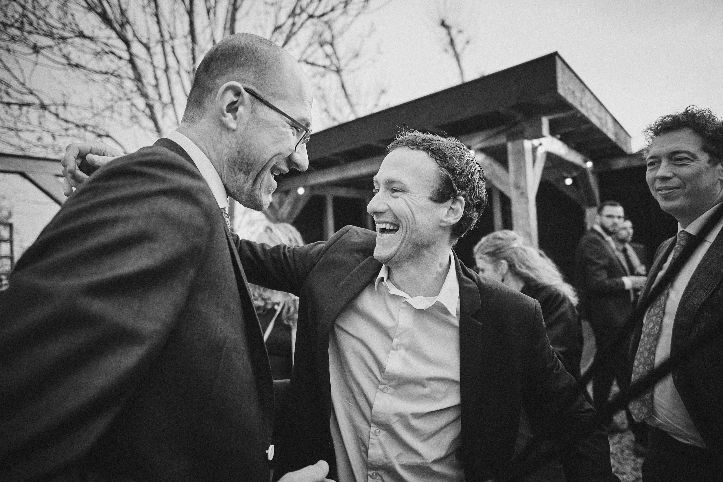 Bruidegom Robbert straalt van geluk terwijl gastheer hem feliciteert op Boerderij Burgersdijk
