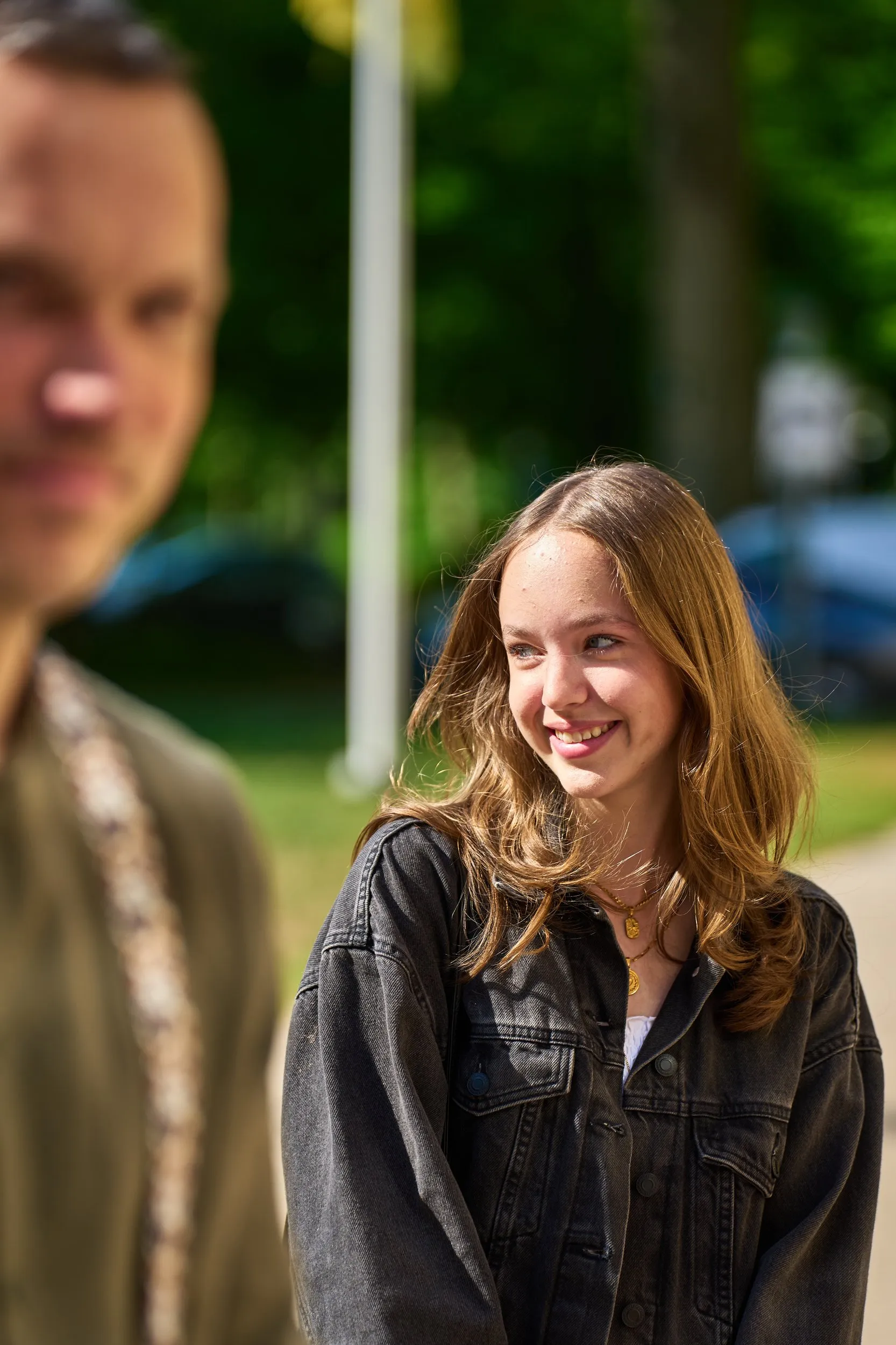 Elise lacht voluit in de zon op Beachclub Titus in Kijkduin, Erik op achtergrond
