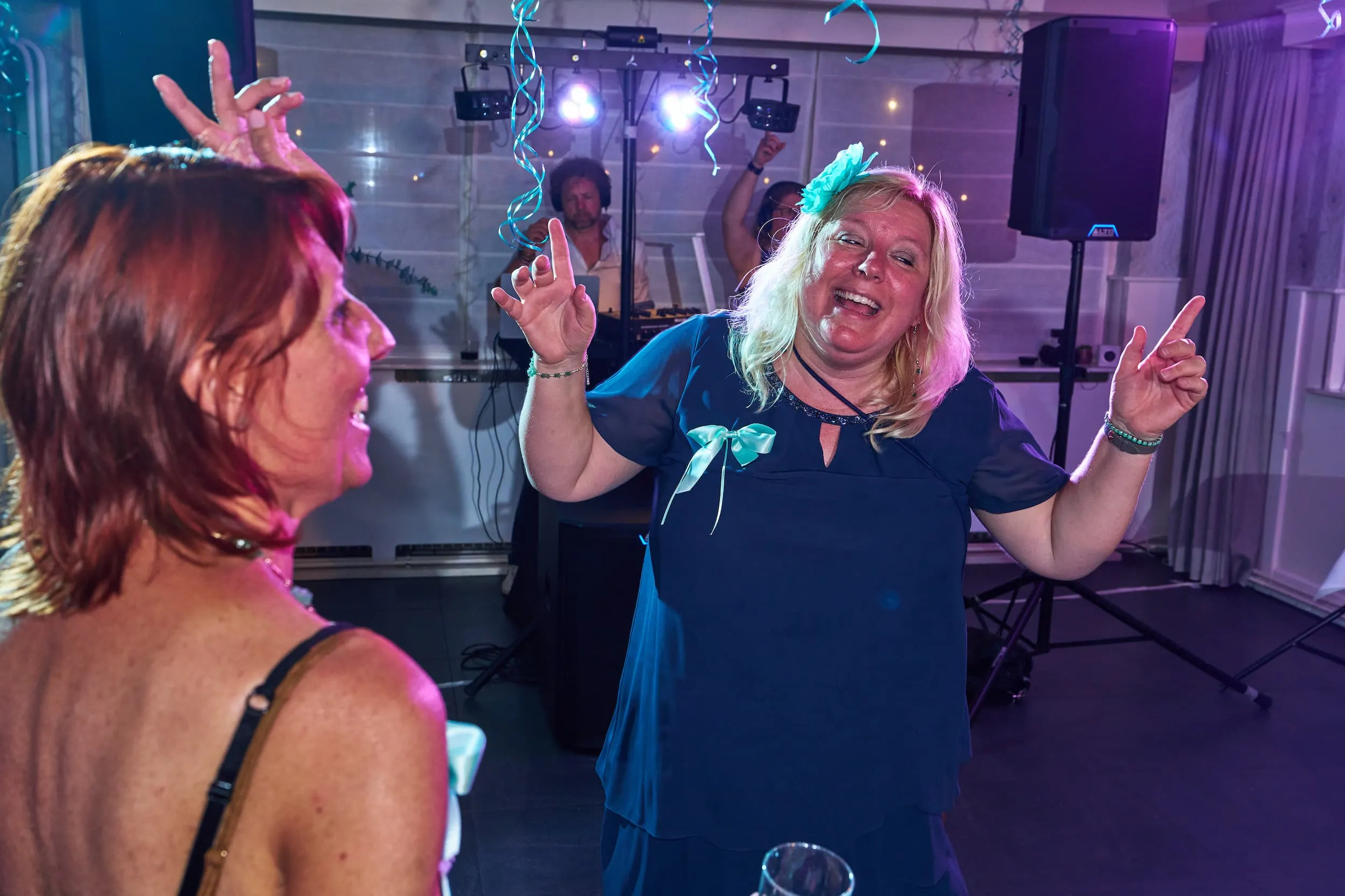 Vrolijke gasten dansen op trouwfeest in zaal met paarse verlichting, feestfotografie receptie — Trouwshoot Stefan Segers