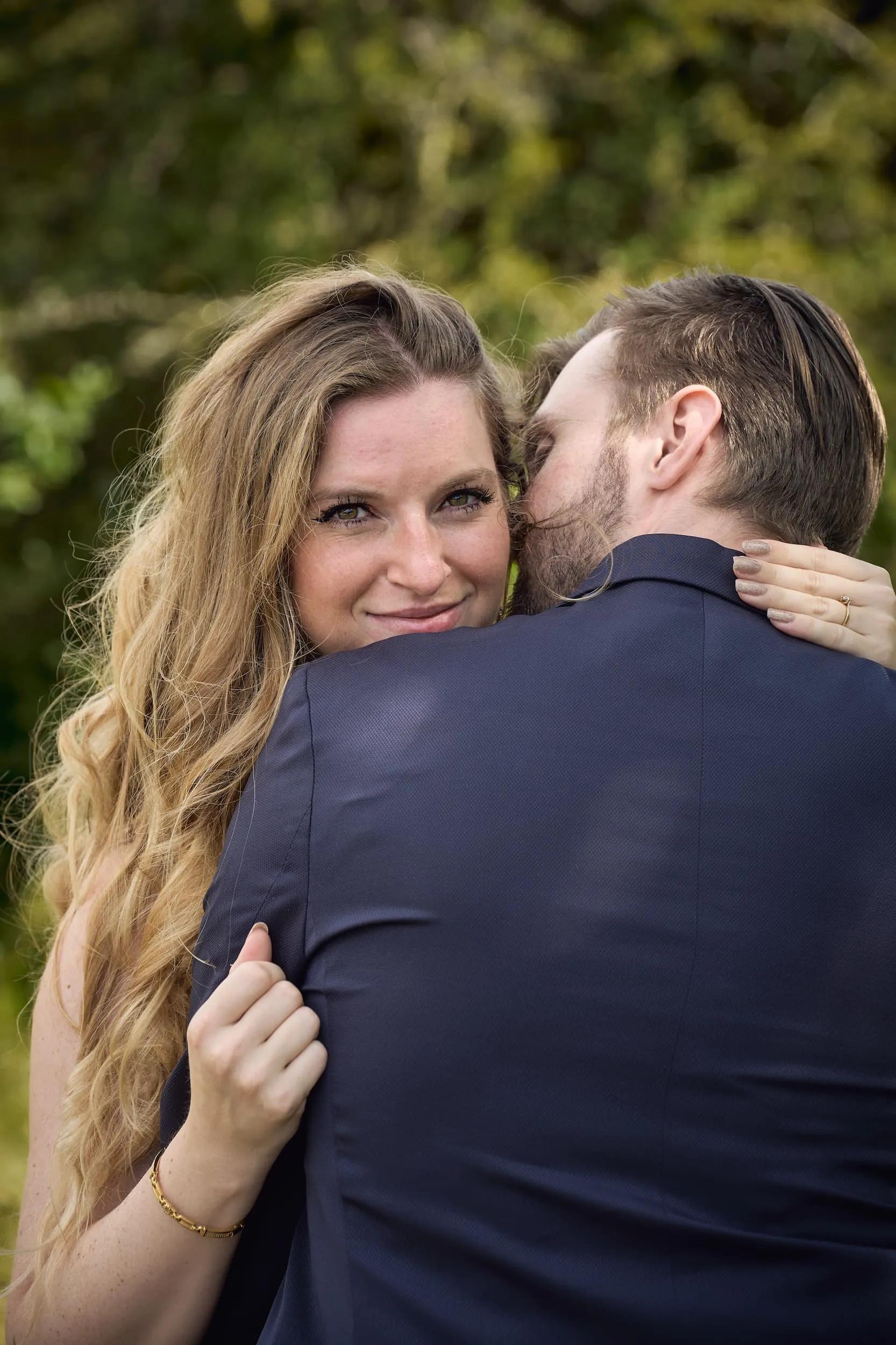 Bruid omhelst bruidegom van achteren in groen landschap, intieme loveshoot moment — Trouwshoot Stefan Segers