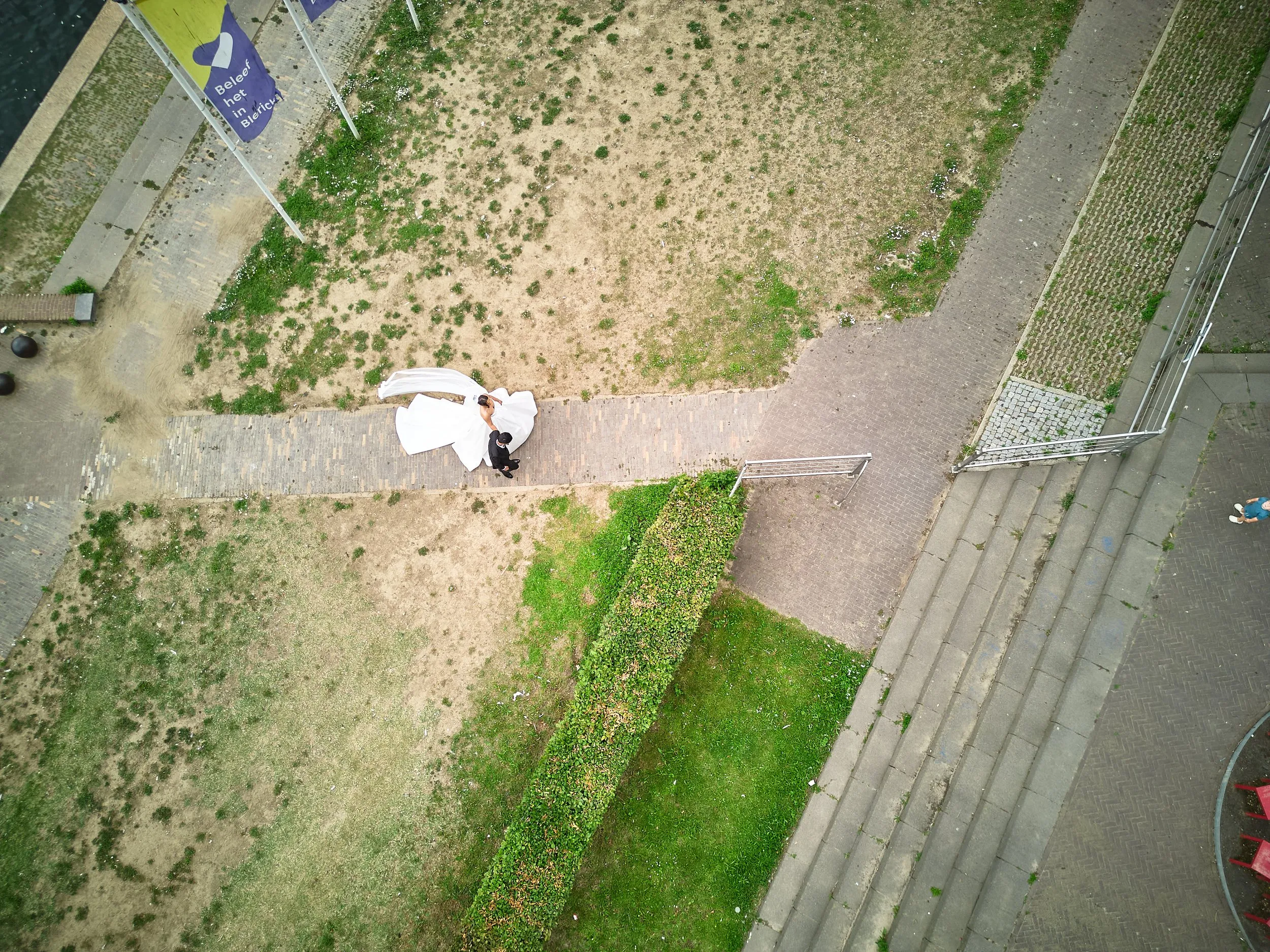 Bruidspaar onder witte paraplu op bakstenen pad in Venlo, luchtfoto
