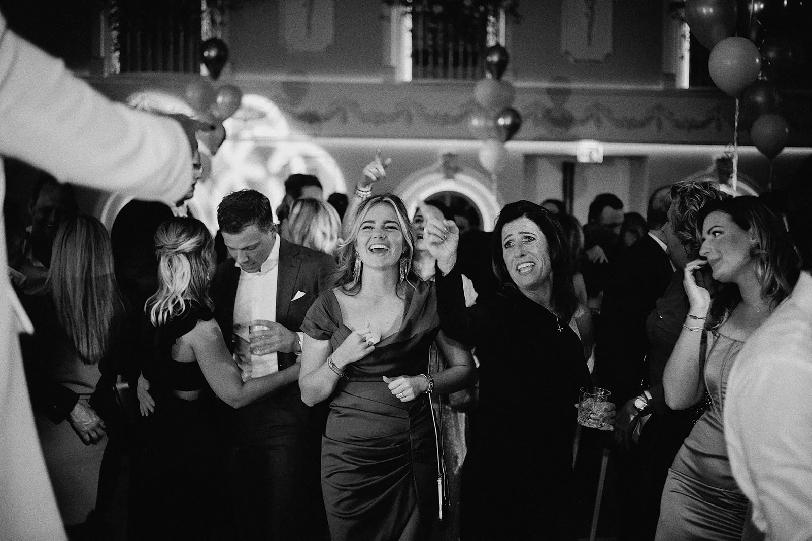 Gezellige bruidsgasten dansen en lachen op het bruiloftsfeest, sfeervolle trouwreportage feestfotografie