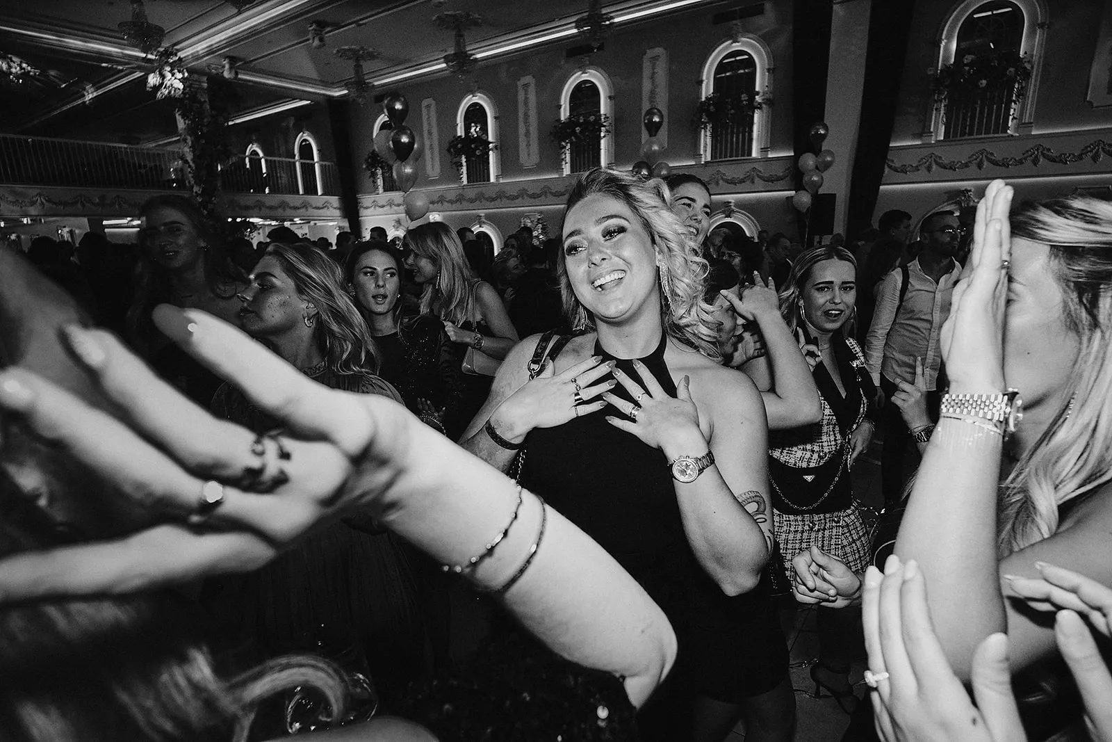 Bruid danst uitgelaten op bruidsfeest omringd door gasten in elegant zaalsetting