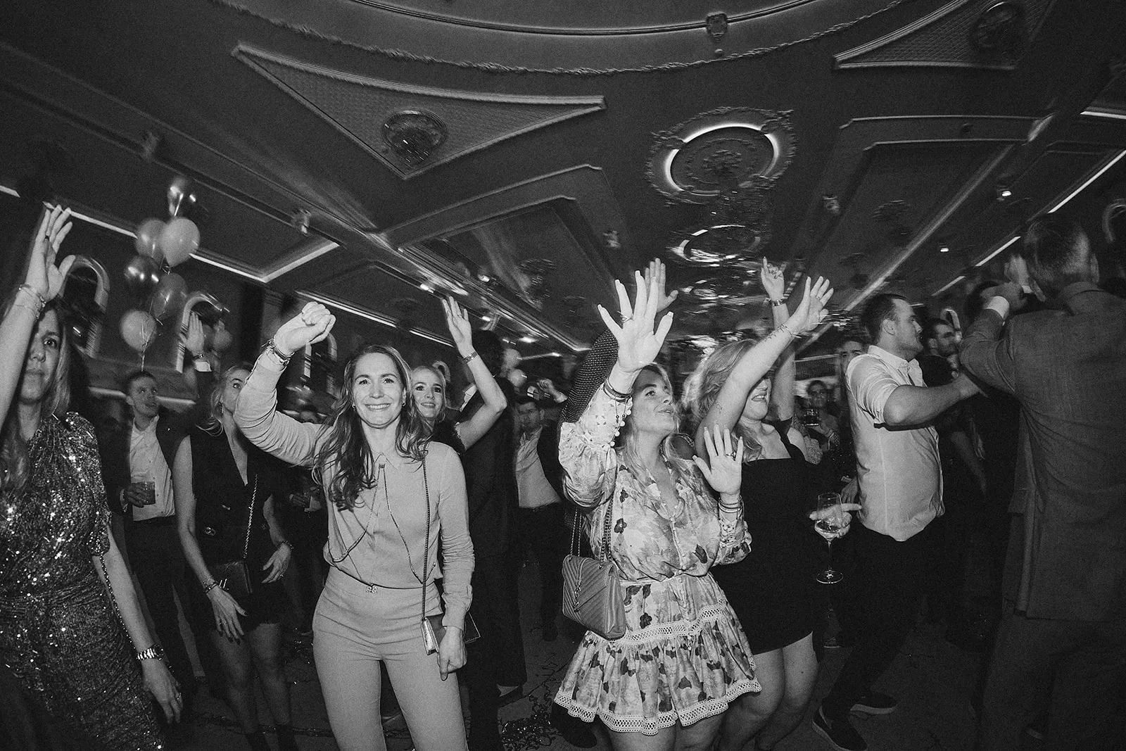 Bruiloftsgasten dansen uitgelaten op trouwfeest, zwart-witfoto van festive sfeer op dancefloor