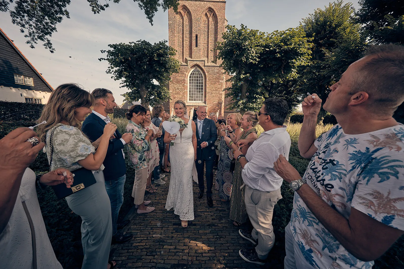 Bruidspaar Bram en Elles danst met gasten bij historische kerk Het Dikke Torentje, vrolijke trouwreportage
