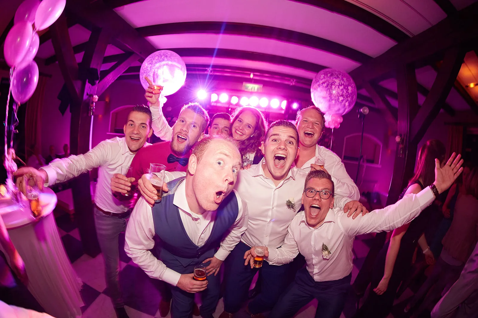 Bruidspaar Mark en Kelly feesten met gasten op dansfeest, paarse neonverlichting