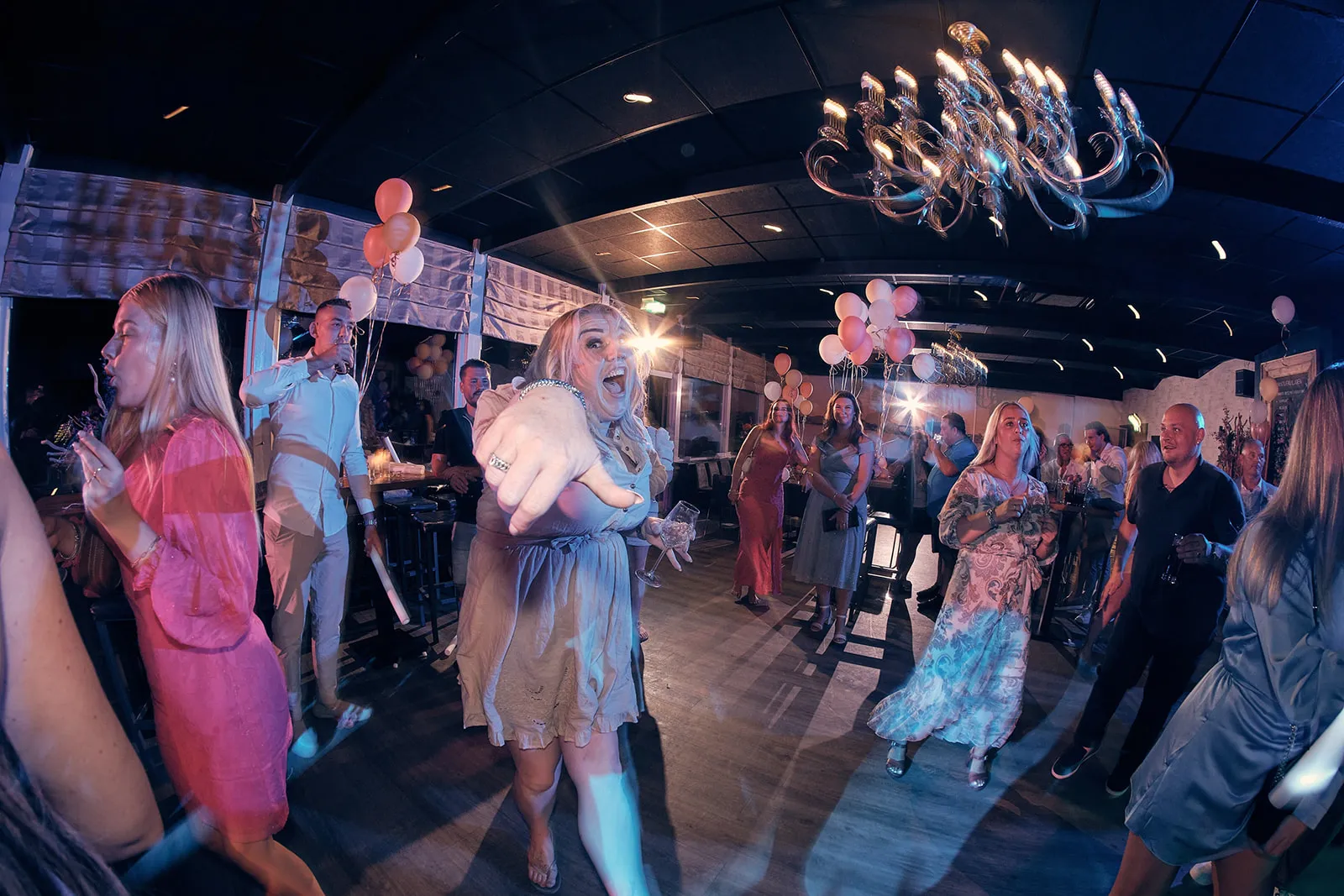 Bruidspaar Jacky en Jordy dansen met gasten op feestje, roze ballonnen en moderne kroonluchter, trouwfeest Wantij Paviljoen D