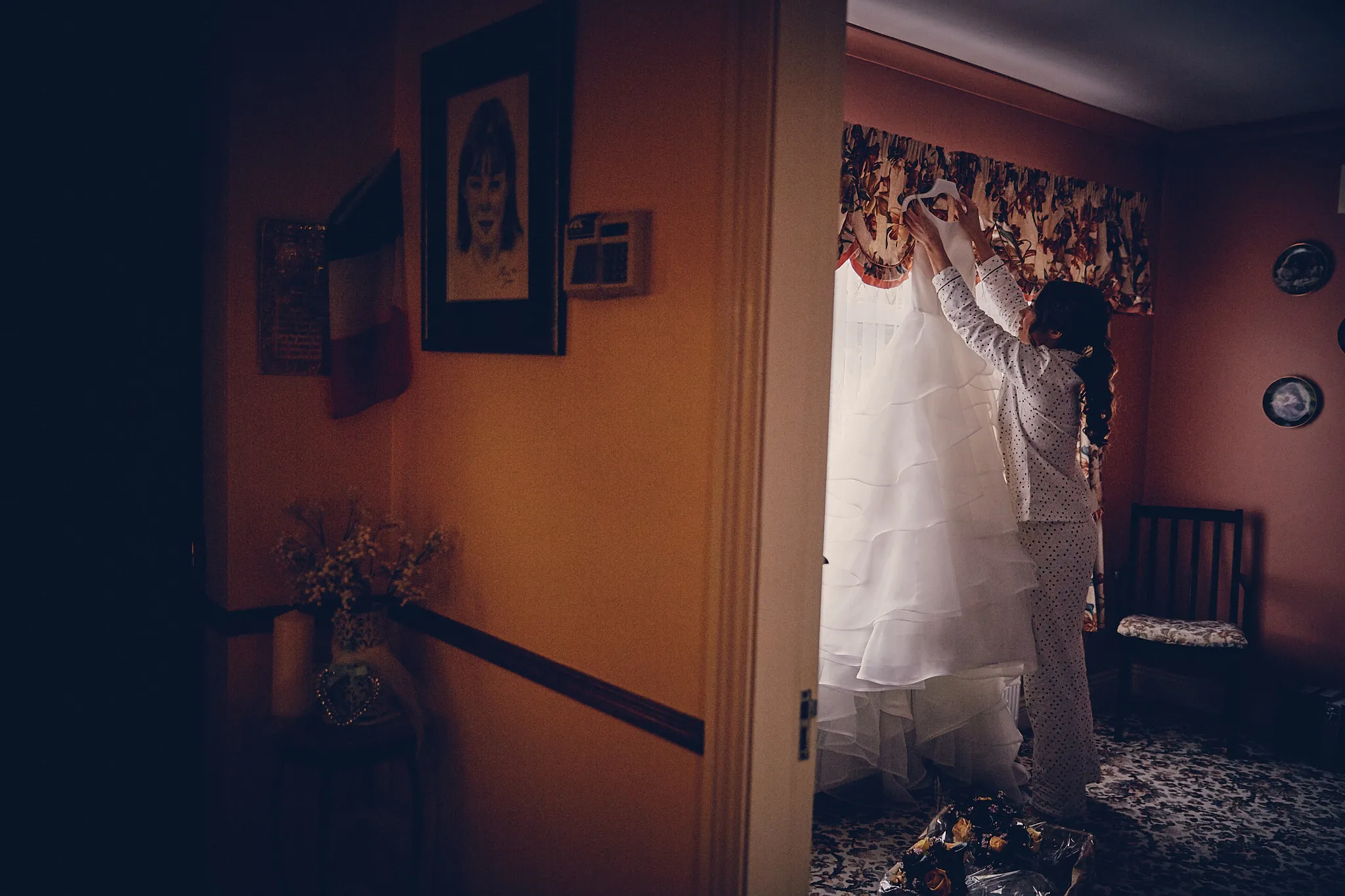 Bruid in witte trouwjurk hangt sluier op in kleurrijke hotelkamer, destination wedding voorbereiding — Trouwshoot Stefan