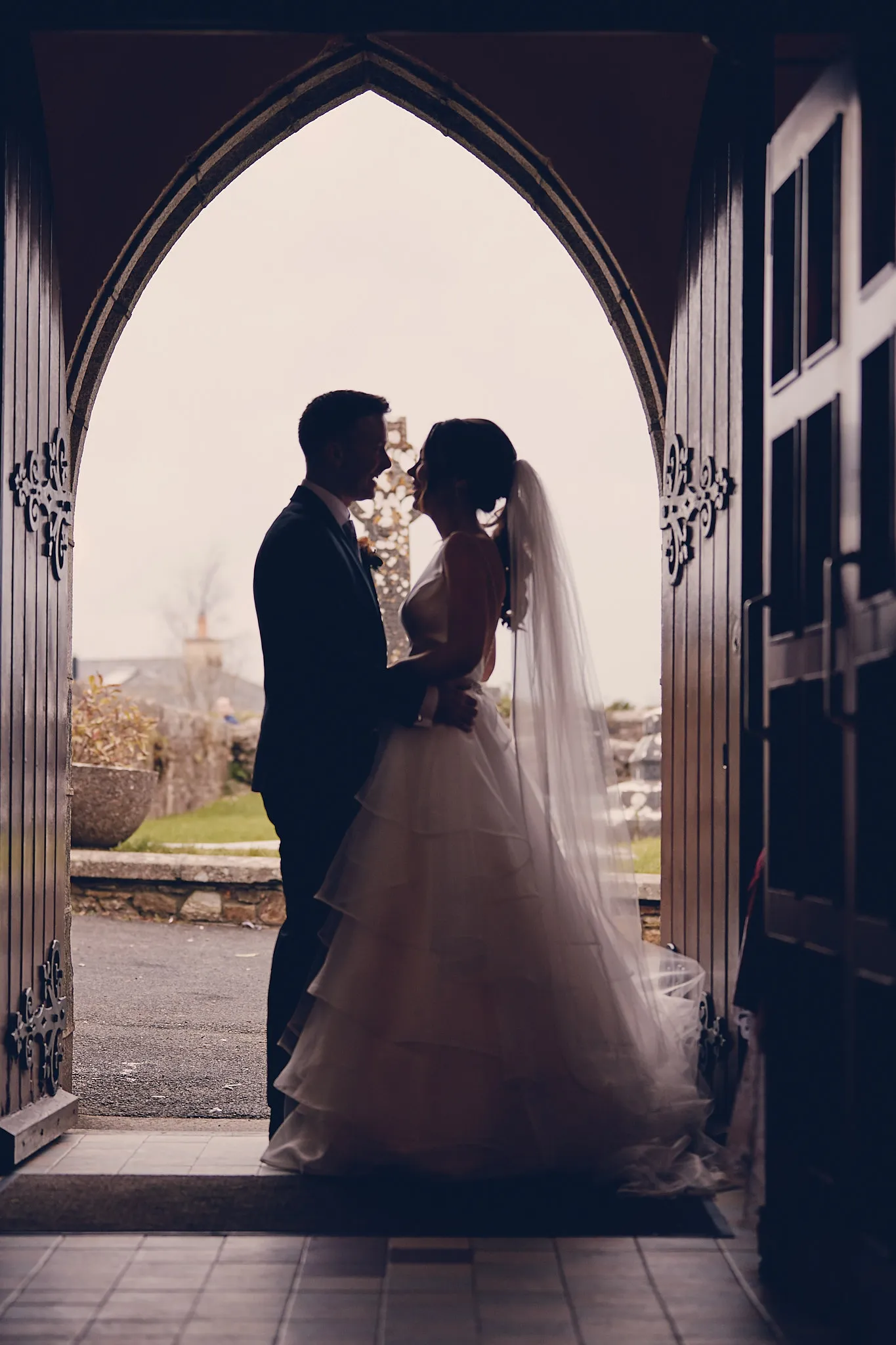 Bruidspaar in gotische deuropening, destination wedding met landgoed uitzicht, romantische trouwfotografie — Trouwshoot