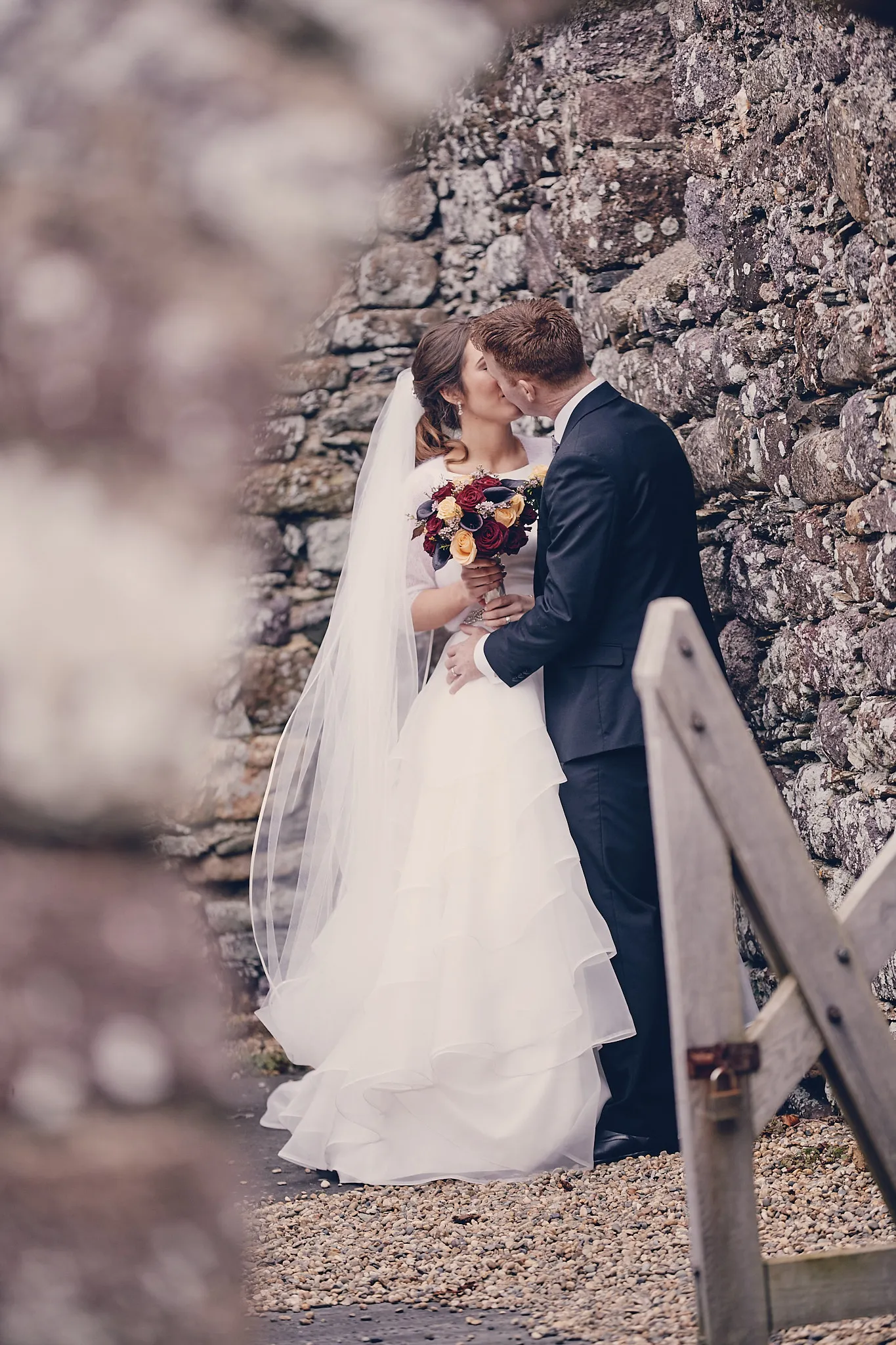 Bruidspaar kust tegen stenen muur, bruidje met sluier en bloemen, destination wedding fotografie — Trouwshoot Stefan Seg