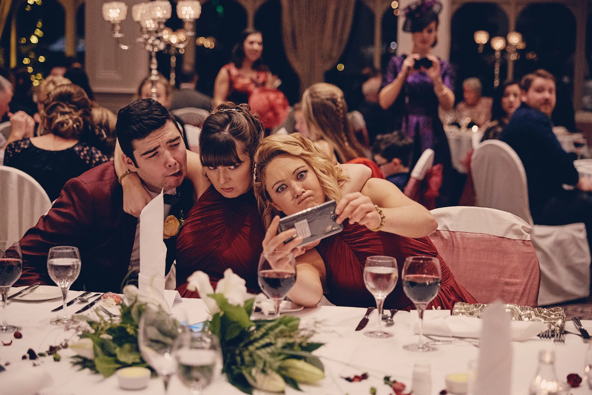 Gasten nemen selfie bij bruiloftstafel, destination wedding met elegante decoratie en gouden kroonluchters — Trouwshoot
