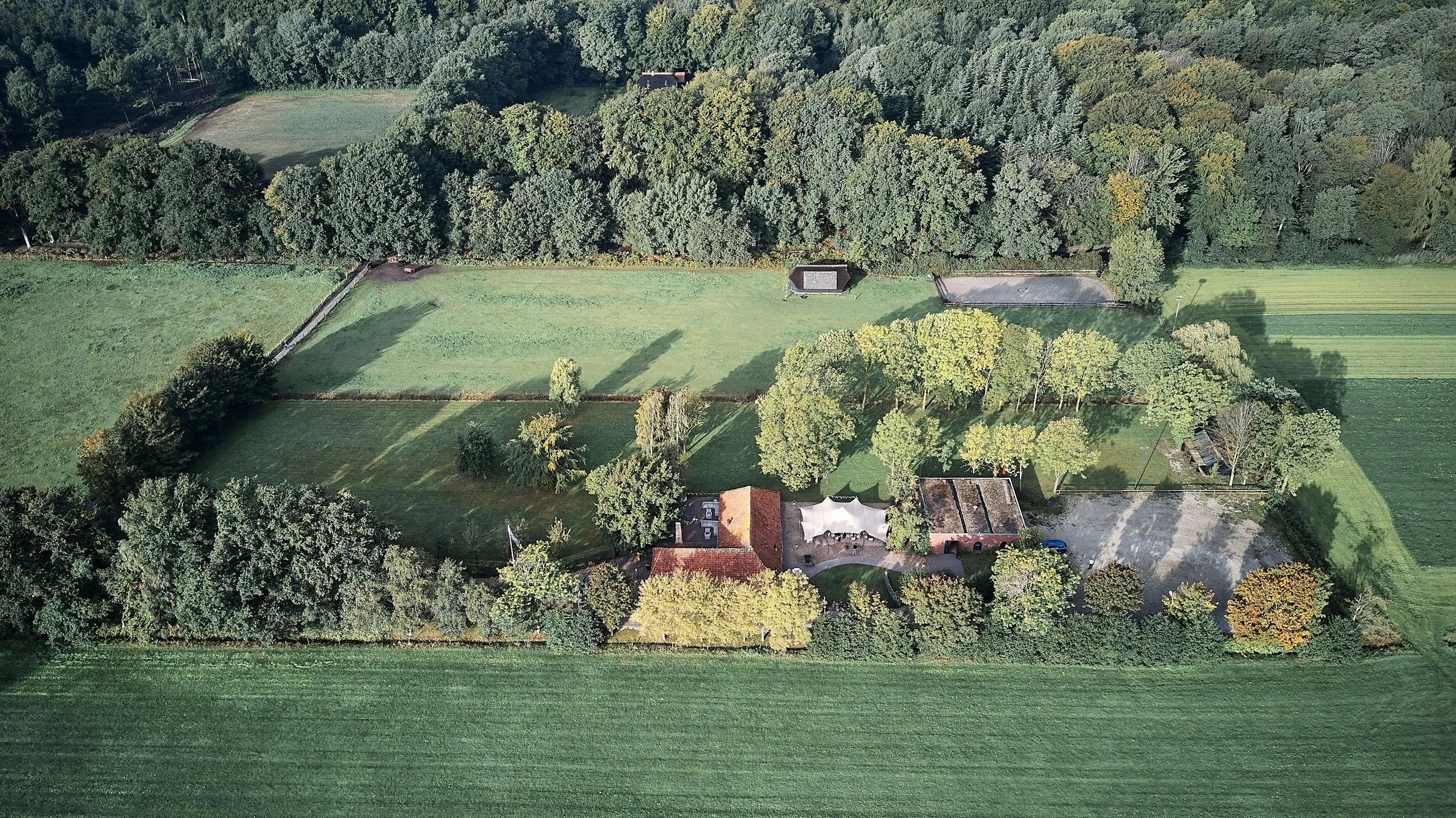Luchtfoto van Hoeve Sparredam in Hoevelaken met witte feesttent waar Menno en Esther trouwen