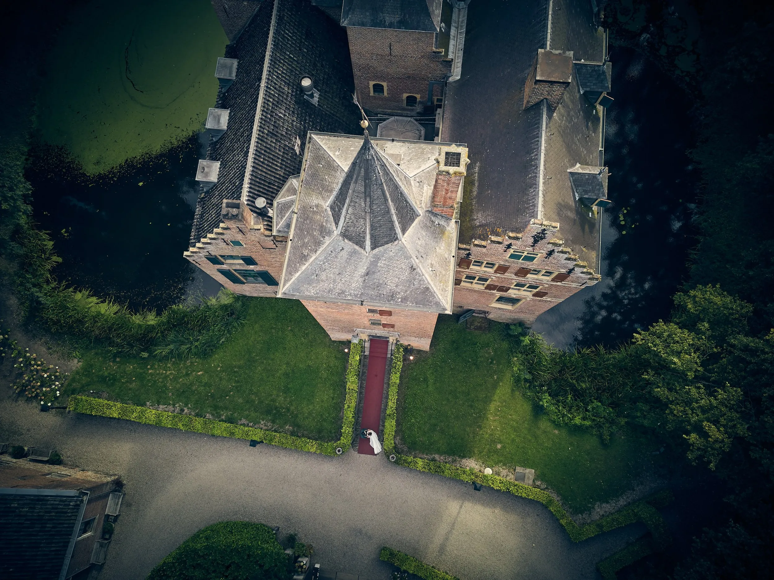 Bruidspaar Renee en Fabian lopen over het rode looppad naar Kasteel Wijnenburg in Echteld - luchtfoto