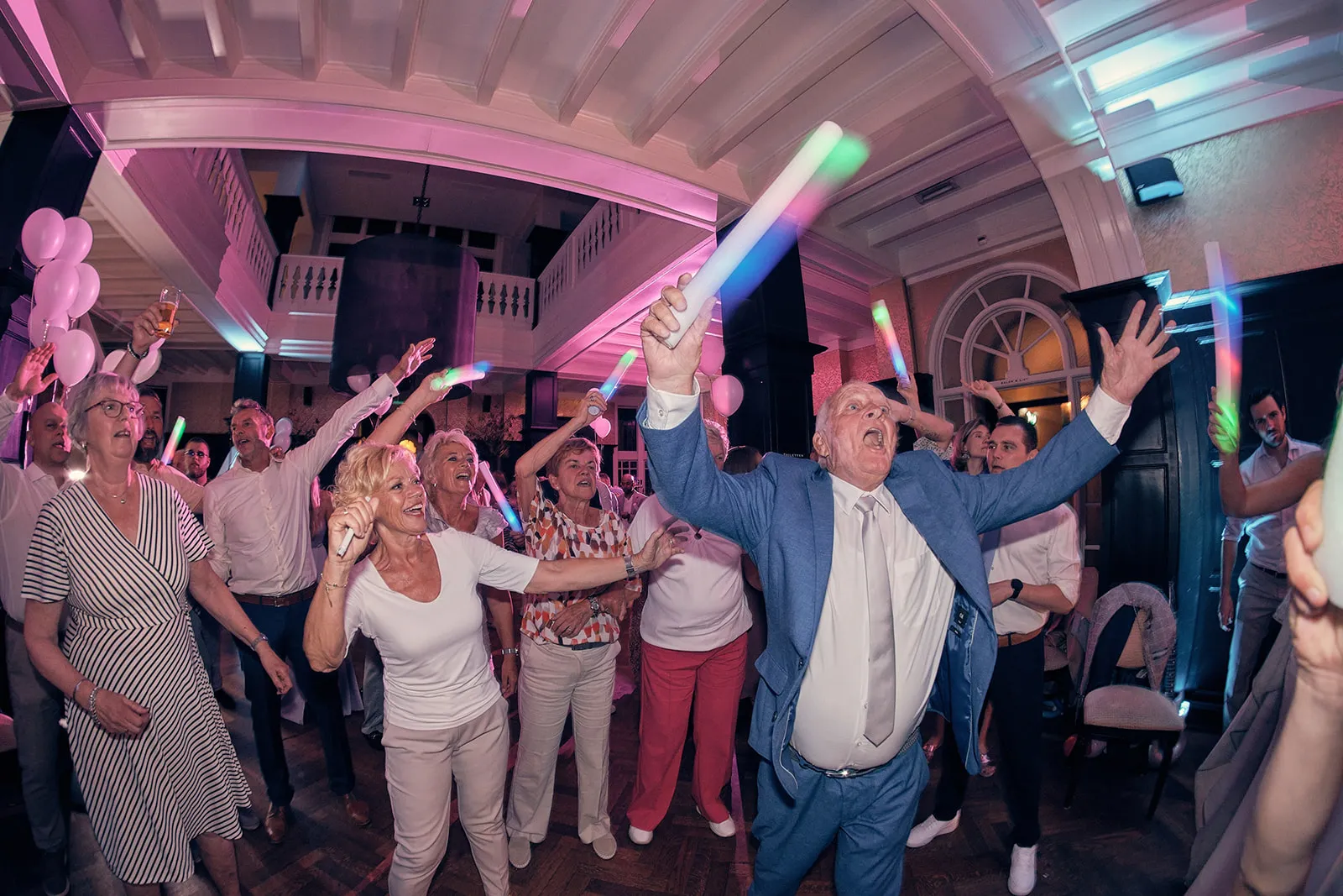 Bruidsgasten dansen feestelijk met glow sticks op trouwreceptie Kasteel De Hooge Vuursche, huwelijk Dennis en Kim - Trouwshoo