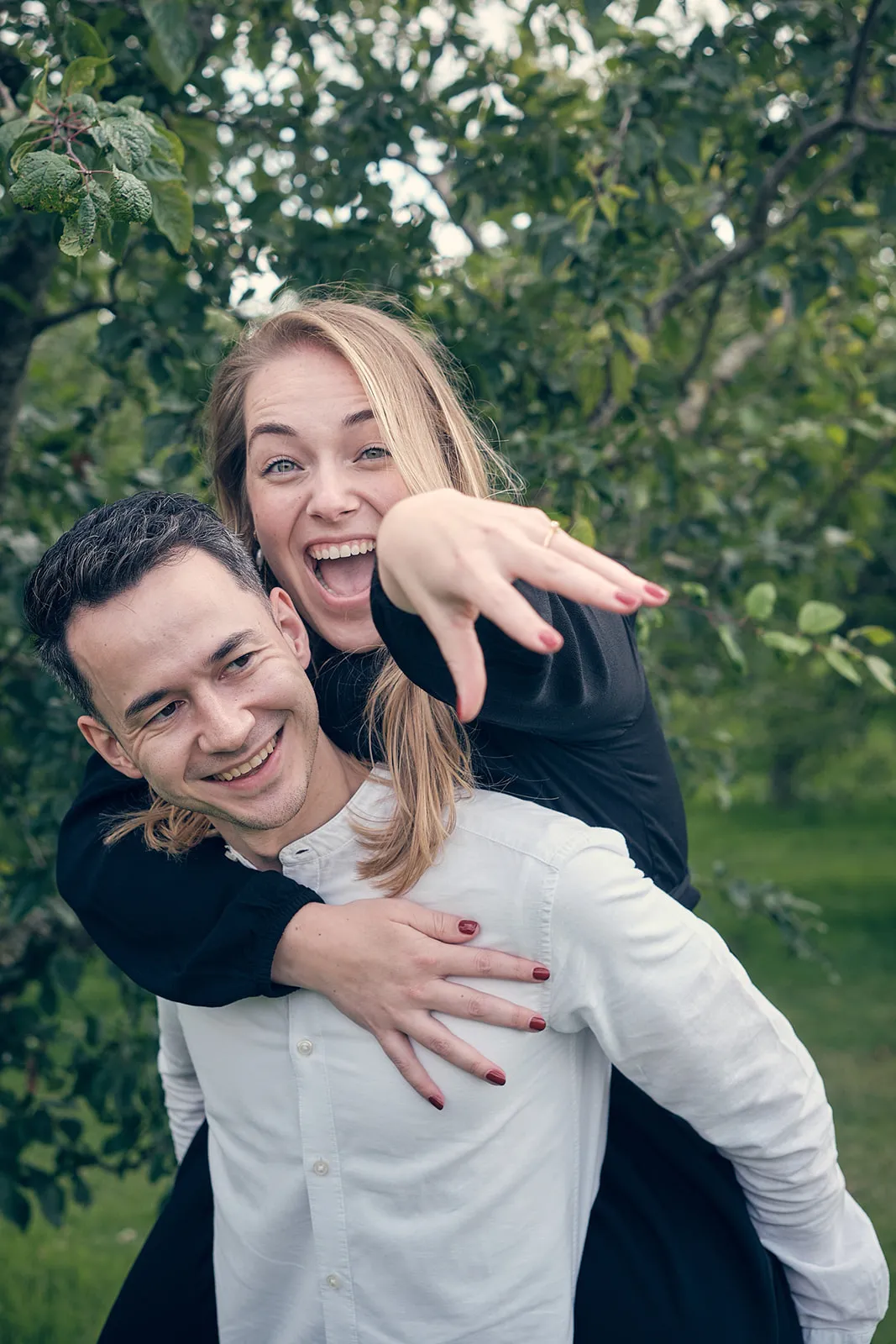 Bruidspaar Marinka en Wai Ho speels in groene tuin bij Muiderslot Muiden, huwelijksaanzoek loveshoot