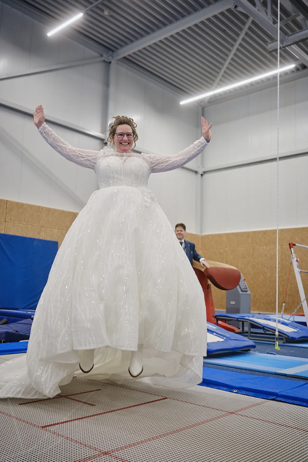 Bruid Christa springt juichend op trampolines in Gymworld Zoetermeer, vrolijke trouwreportage