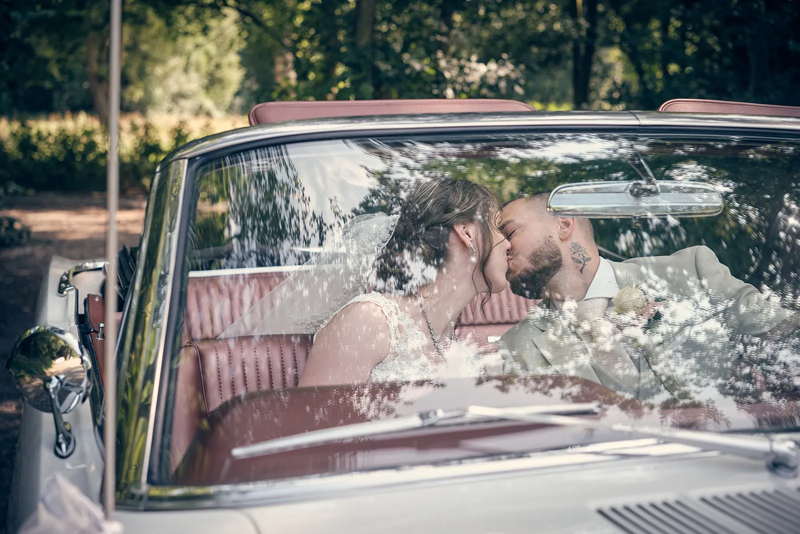 Bruidspaar Robin en Wendy kussen in klassieke cabriolet bij Het Wapen van Zoetermeer, trouwreportage Westerpark