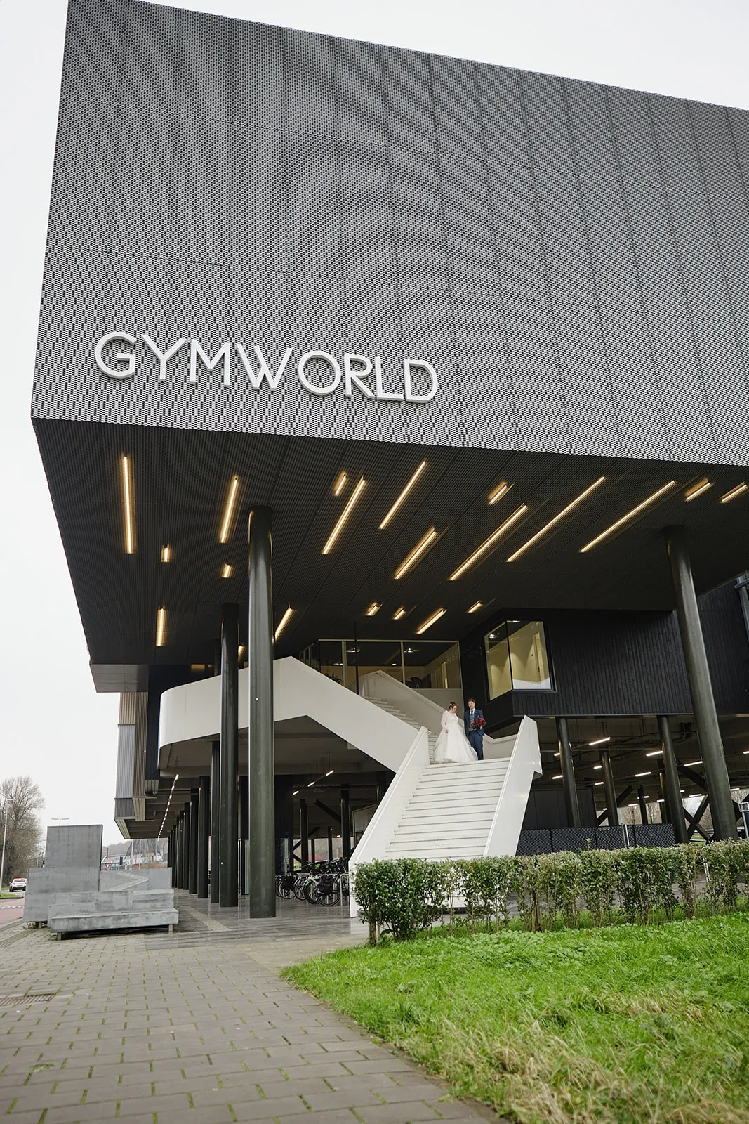 Bruidspaar Christa en Gerco op wit trap bij Gymworld Zoetermeer, moderne trouwreportage