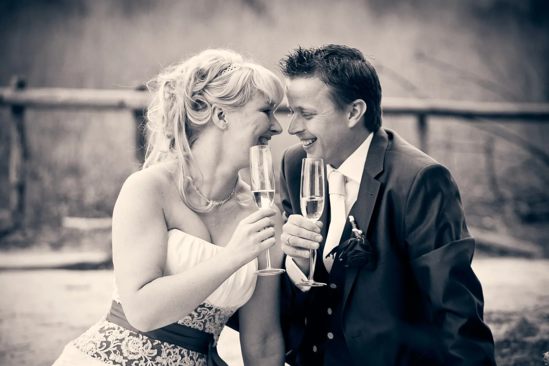 Een bruid en bruidegom lachen samen terwijl ze champagne drinken op hun bruiloft.