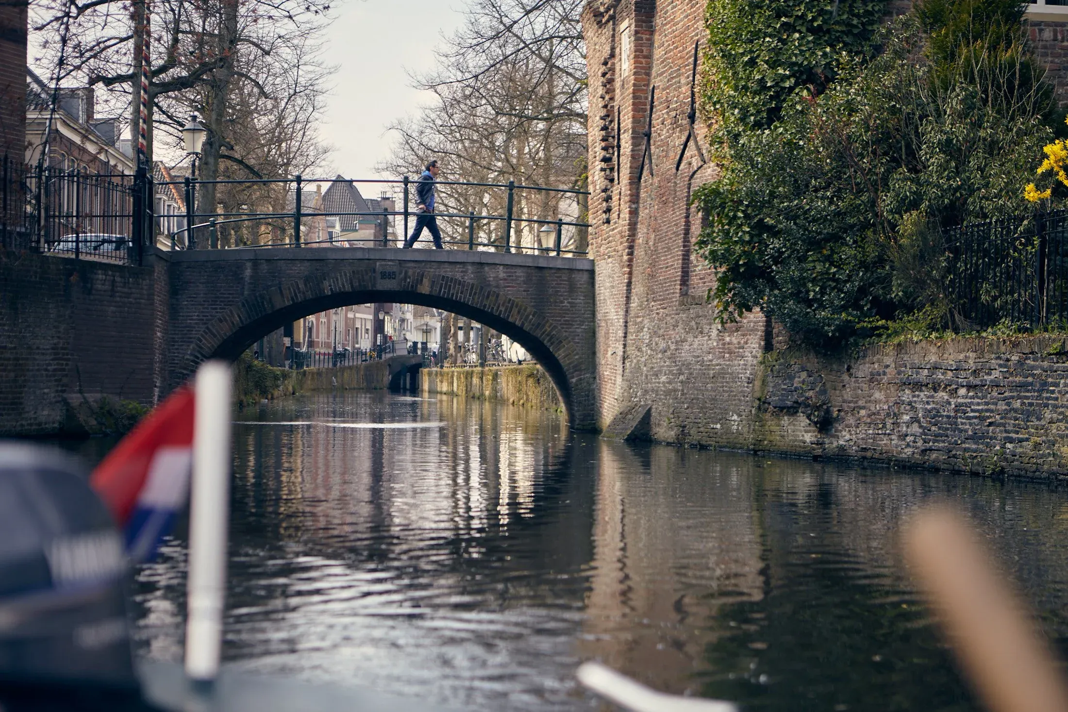 Een stenen bruggetje over een smalle gracht in Amersfoort, gezien vanaf een bootje