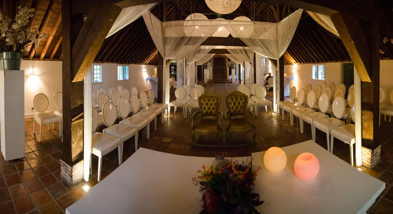 De lege trouwzaal met witte stoelen en lichtjes