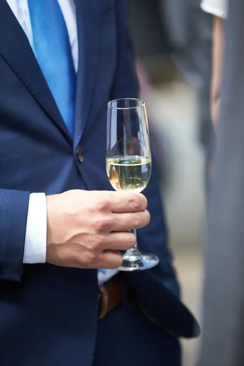 Een champagneglas in de hand van een gast