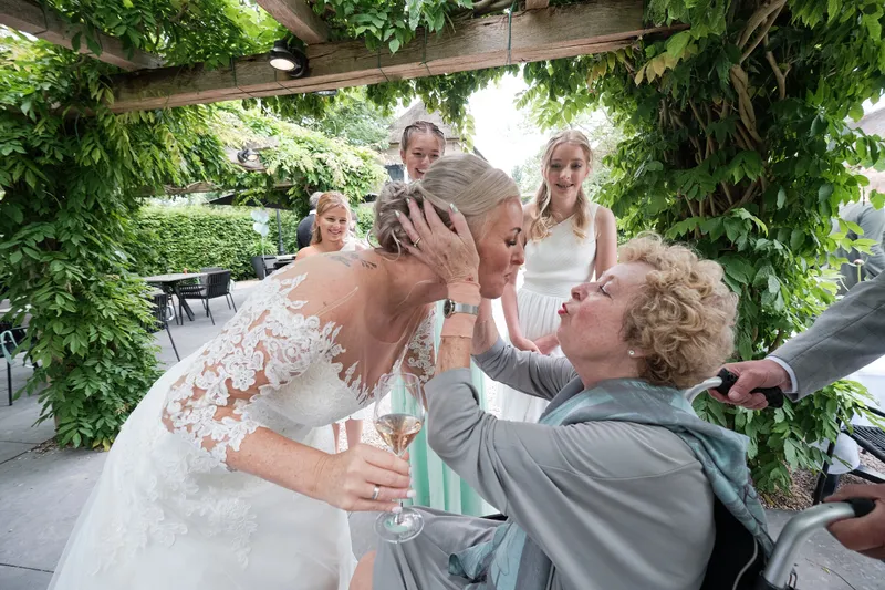 Marleen krijgt een kus van een gast onder de pergola