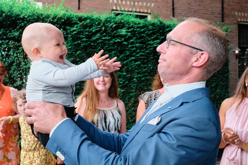Een gast tilt een baby hoog op in de tuin