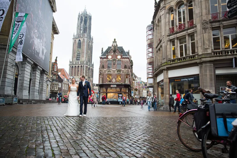 Een brede straat met de Domtoren, Tessa en Wessel klein in beeld