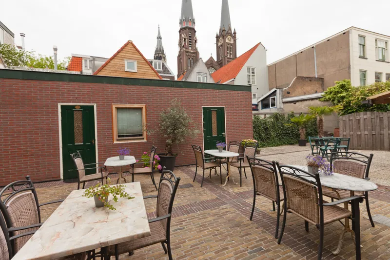 De binnenplaats met tafeltjes en de kerktorens van Delft erboven