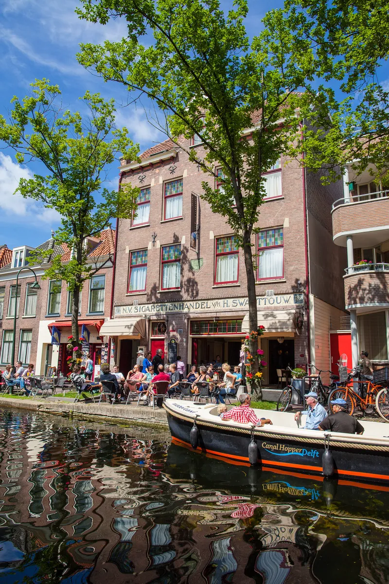 Het hotel aan de gracht, met het terras en een bootje op het water