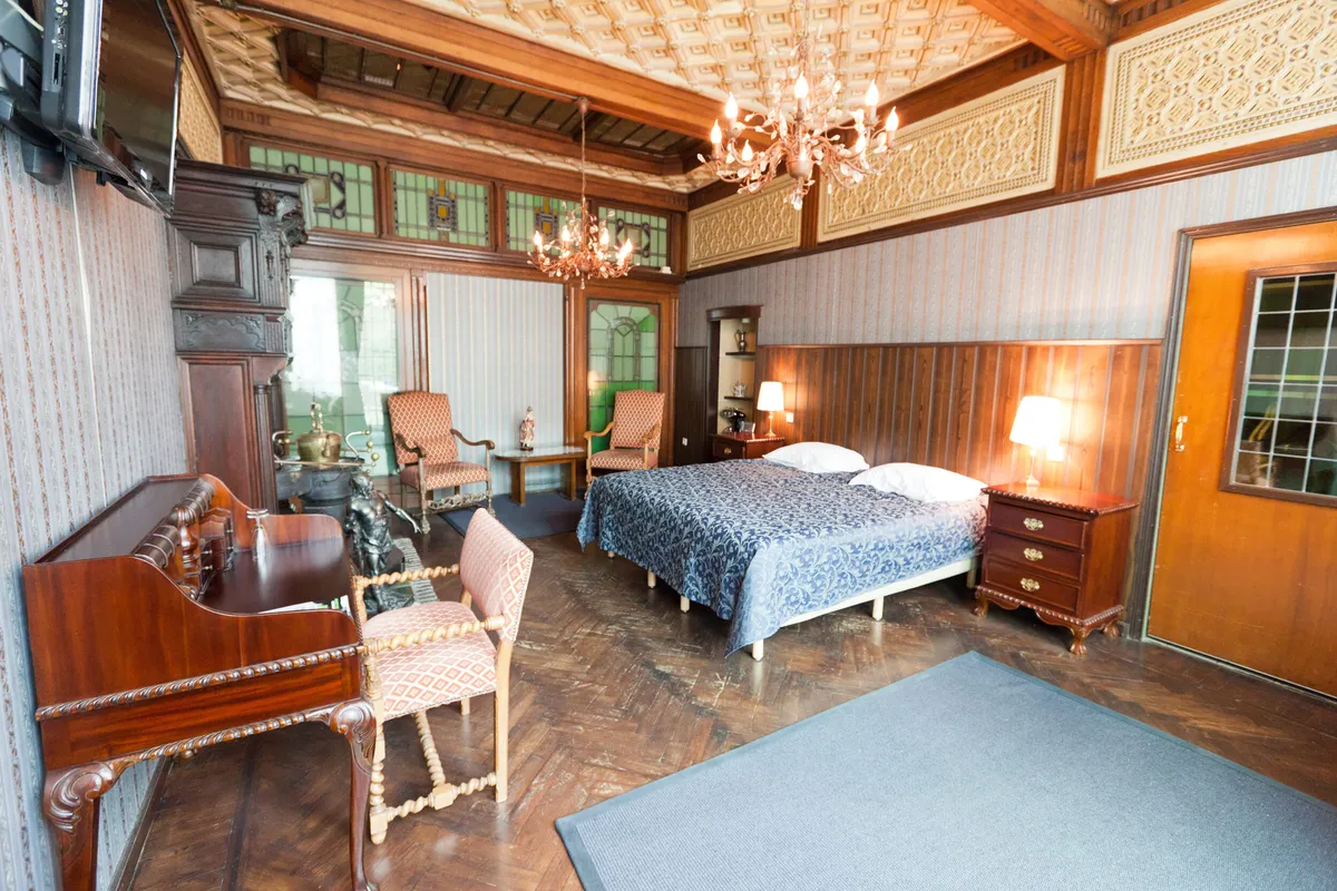 Een ruime hotelkamer met kroonluchter en een bureau bij het raam