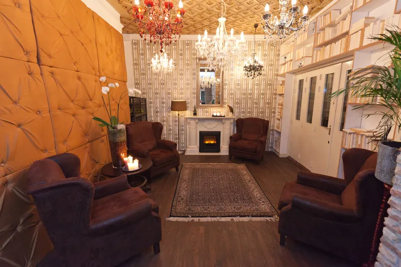 De lounge met boekenkasten, kroonluchters en leren fauteuils