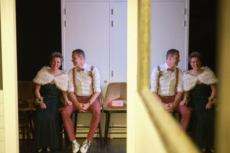 Esther en Bart wachten in de gang, gespiegeld in de deur