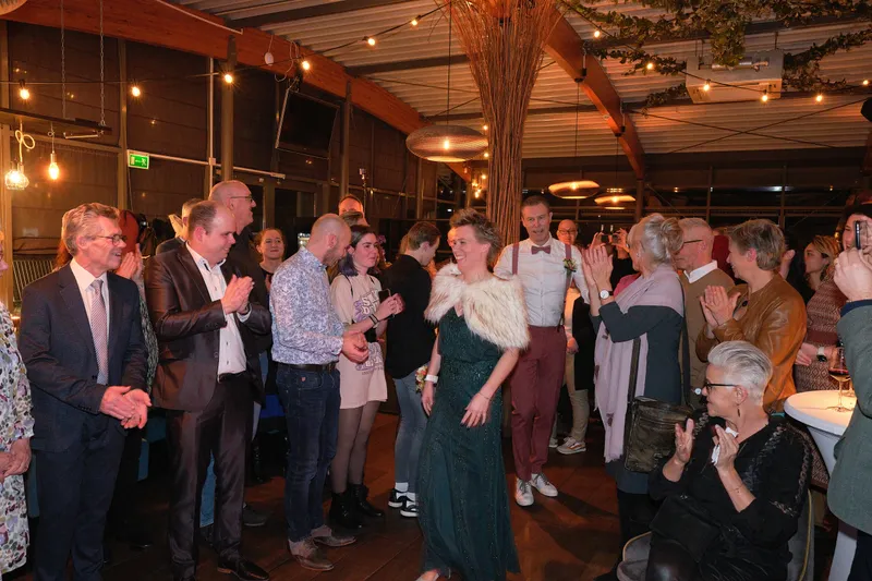 De gasten staan om de tafel heen, nog niet wetend wat er gaat gebeuren