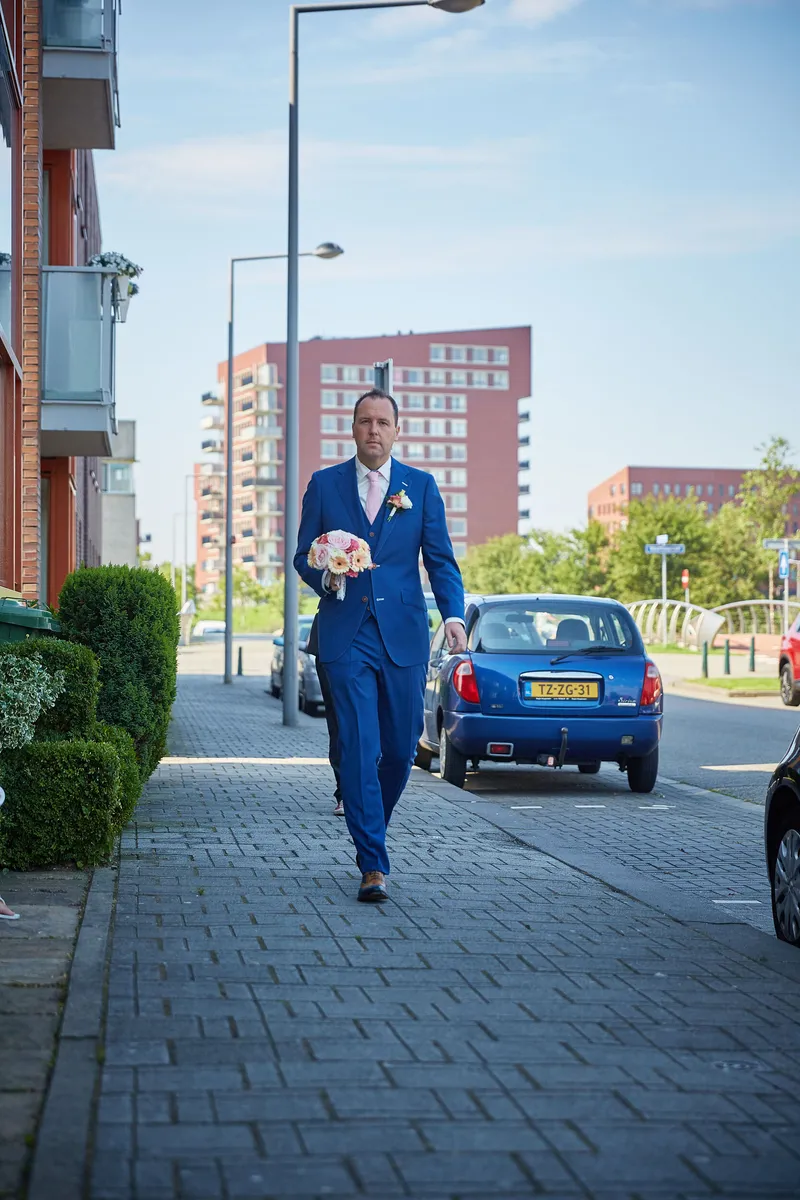 Herman loopt in zijn blauwe pak over straat naar het huis