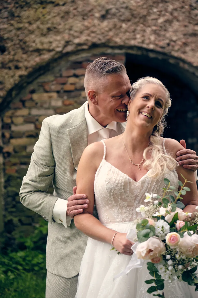 Marco en Tamara lachen onder een oude bakstenen boog