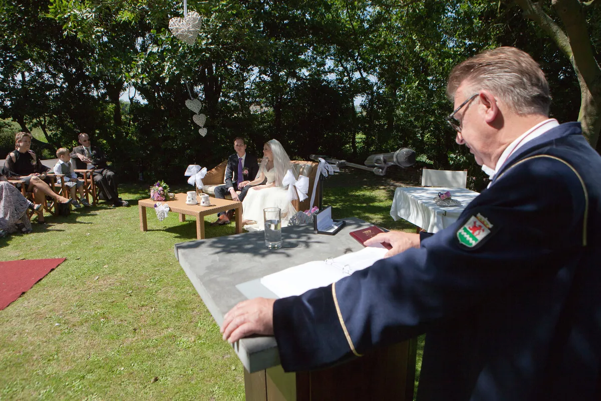 De ceremonie in de tuin van De Viersprong, met de trouwambtenaar achter de tafel en de gasten op het gras