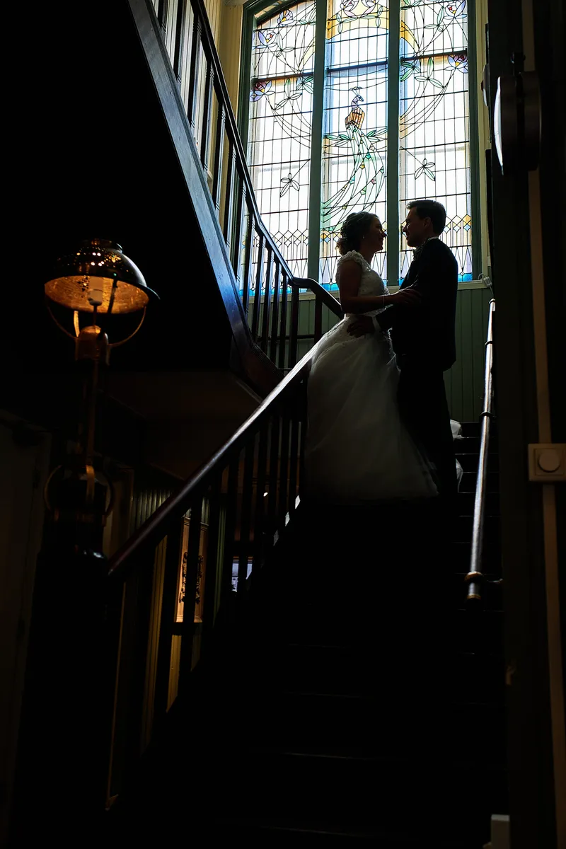 Kirsten en Jouke als silhouet op de trap met glas-in-lood