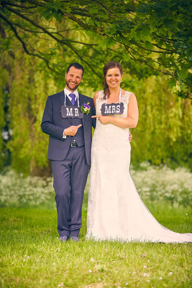 Het bruidspaar met Mr- en Mrs-bordjes in het gras