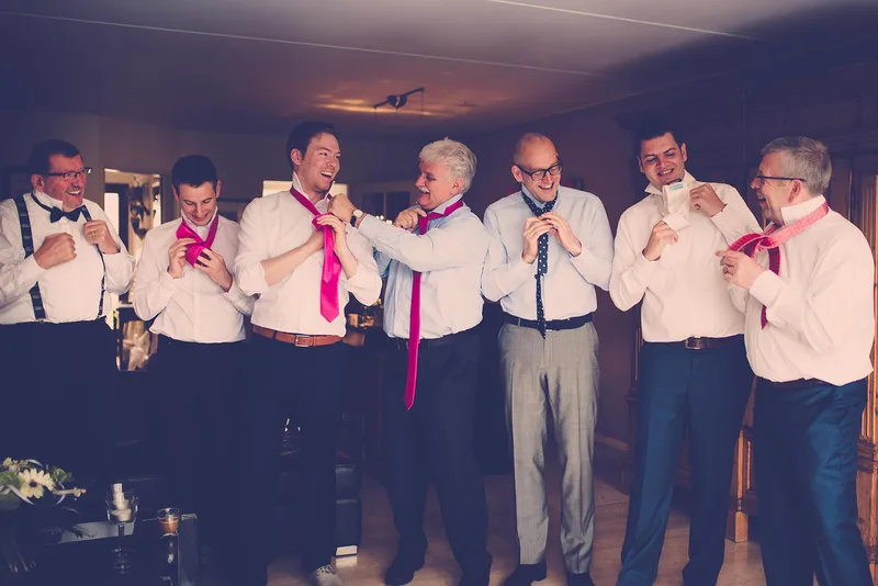 Mannen in witte overhemden met roze strikjes en bretels