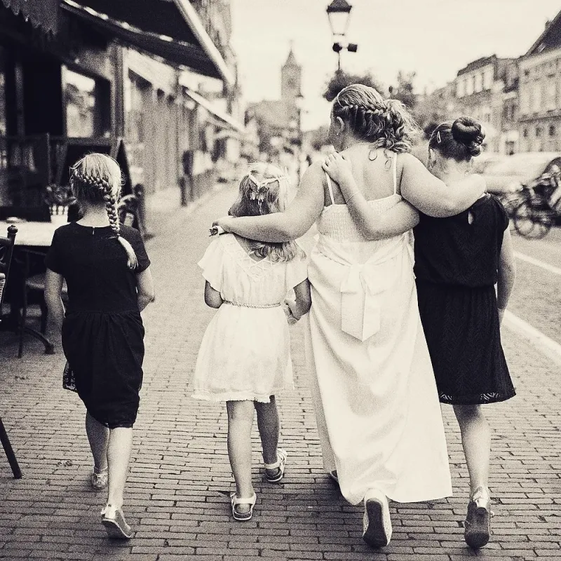 Bruidsmeisjes lopen arm in arm over de keien