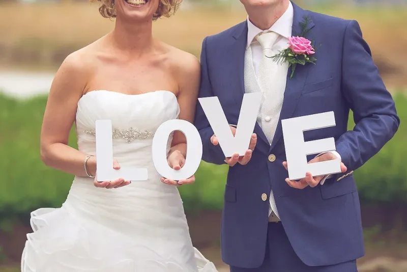 Een bruidspaar met grote witte letters LOVE