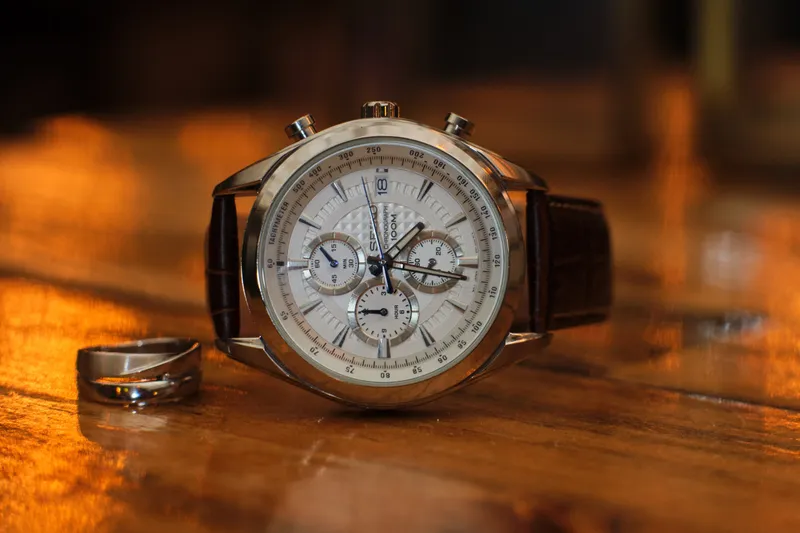 Een horloge en de trouwringen op een houten tafel
