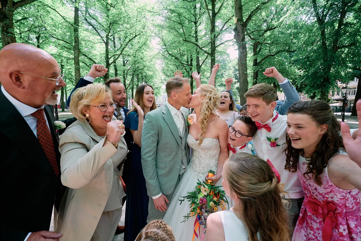 De familie juicht rond Neomi en Michael onder de bomen van het Lange Voorhout