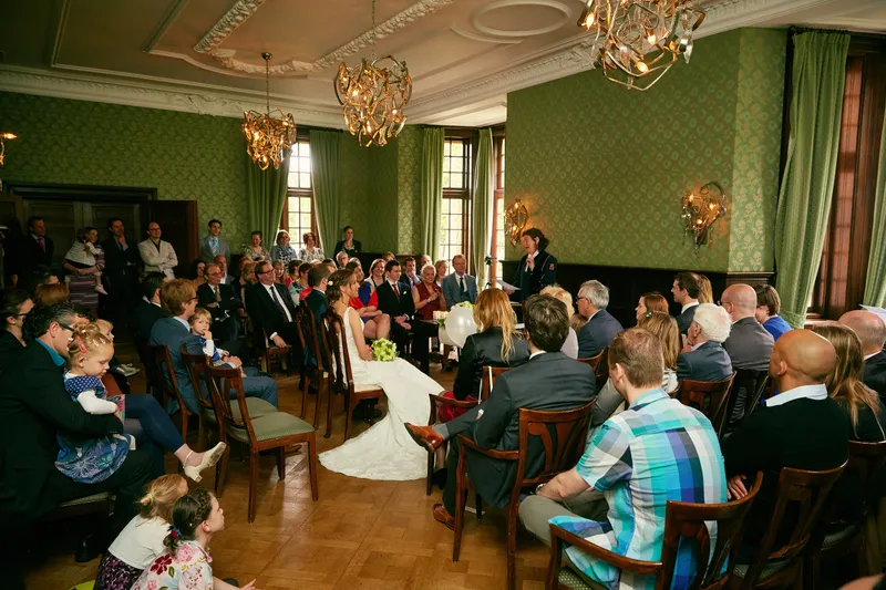 De volle zaal met groen behang tijdens de ceremonie
